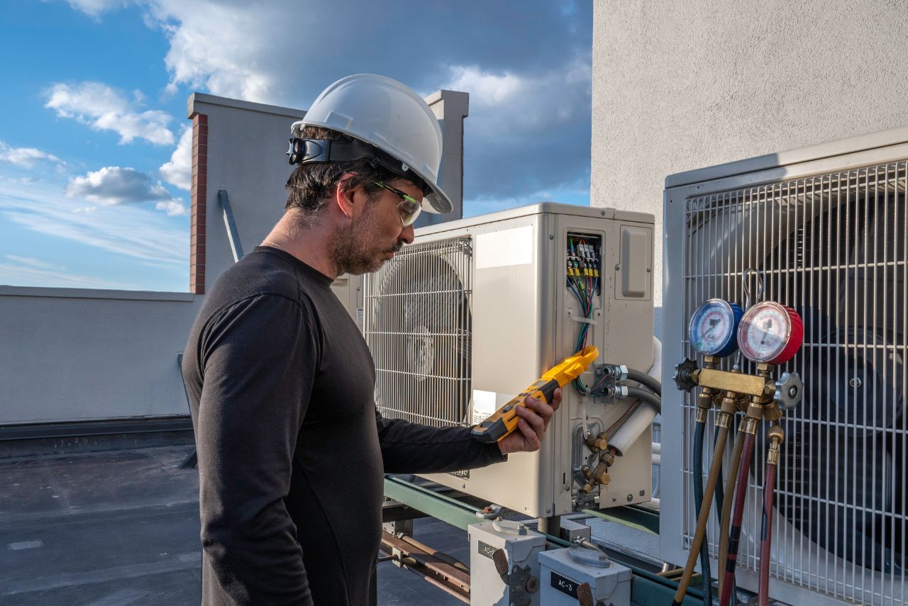The purpose of this image is to serve as an authentic, practical visual anchor for the HVAC Services section on the SpotOn website. By showcasing a realistic, real-world photograph of a technician onsite, it directly reinforces the brand's E-A-T credentials by providing proof of hands-on expertise and operational capability. This builds trust with property owners, improves user experience (UX) layout scannability, and drives local conversions.